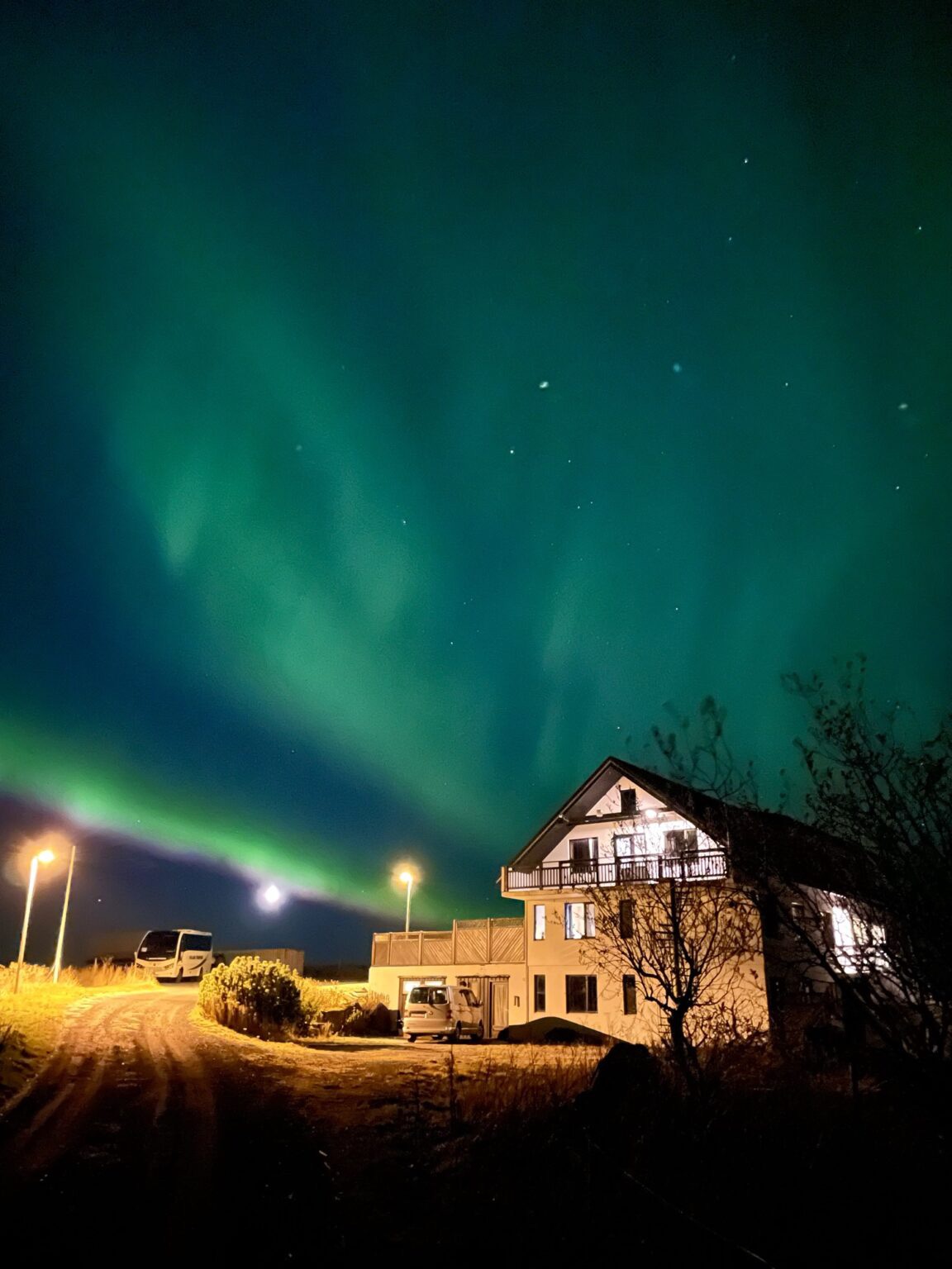 Green Northern Lights cover the sky over a house in Iceland.